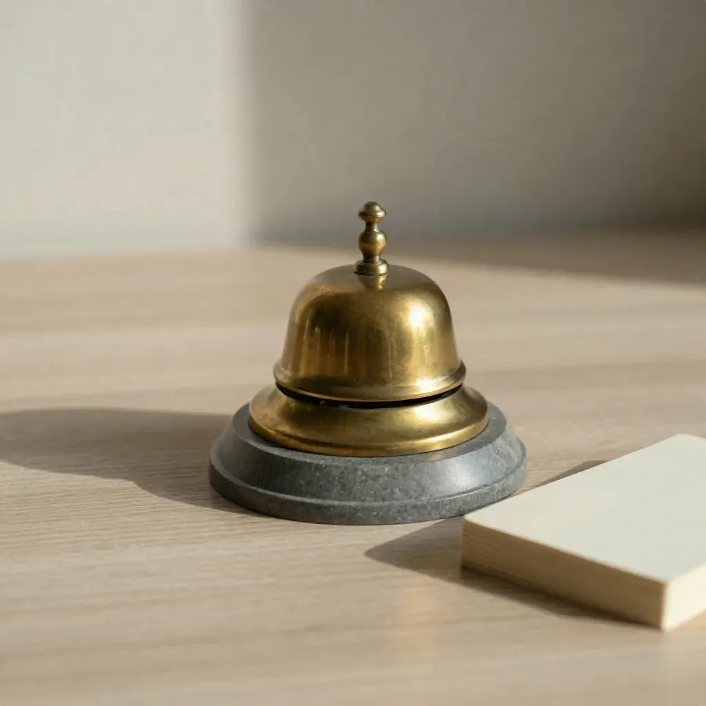 Telefonhalter, Messingklingel und Kartenstapel auf hellem Holz im weichen Seitenlicht.